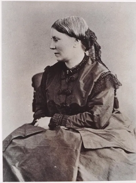 Black and white photograph of Elizabeth Blackwell. She is seated and her face is in profile facing her right. She is dressed in a dark, long-sleeve dress. Her hair is back in a tight, low bun with a dark lace covering on her bun.